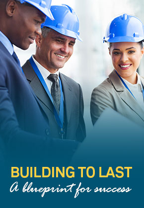3 people with blue hard hats going over a blueprint